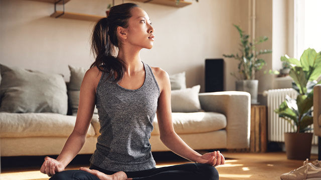 Vrouw in yogahouding op de mat in de woonkamer. 